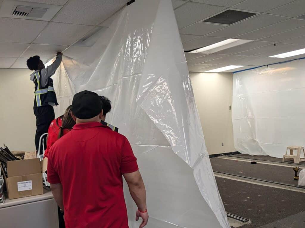 Crew installing plastic dust containment in an office before remodel work