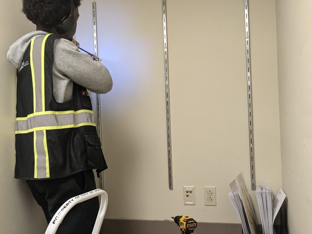 Crew member installing wall hardware during an office remodel