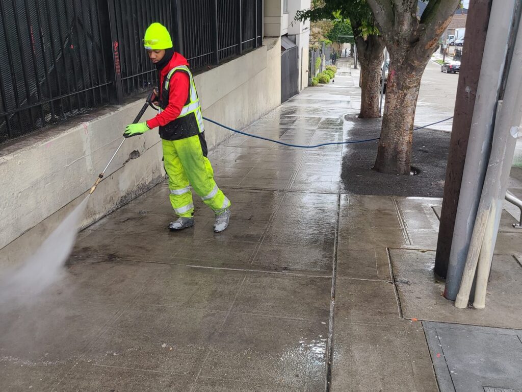 Crew member pressure washing a sidewalk in Seattle Little Saigon