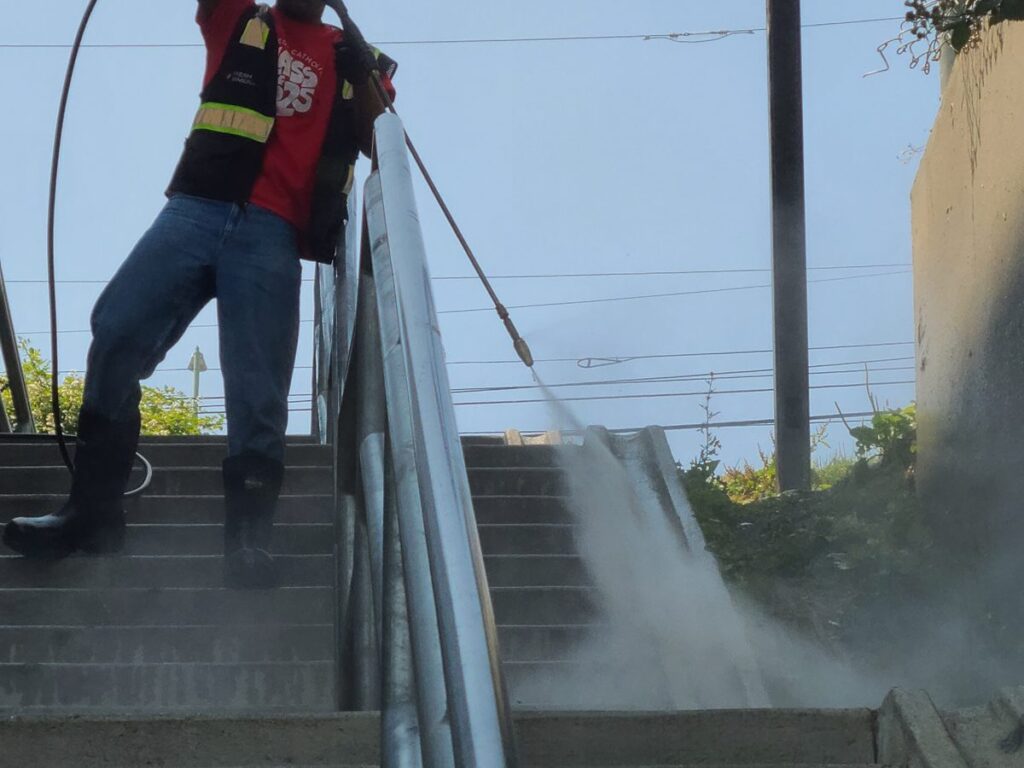 Crew member washing a stairway handrail in the Little Saigon neighborhood