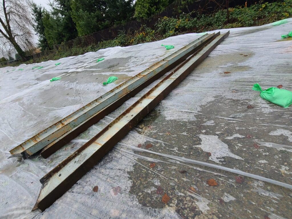 Dismantled bridge steel members staged on containment plastic