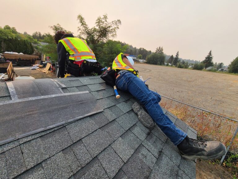 Trainees shingling the tiny home roof