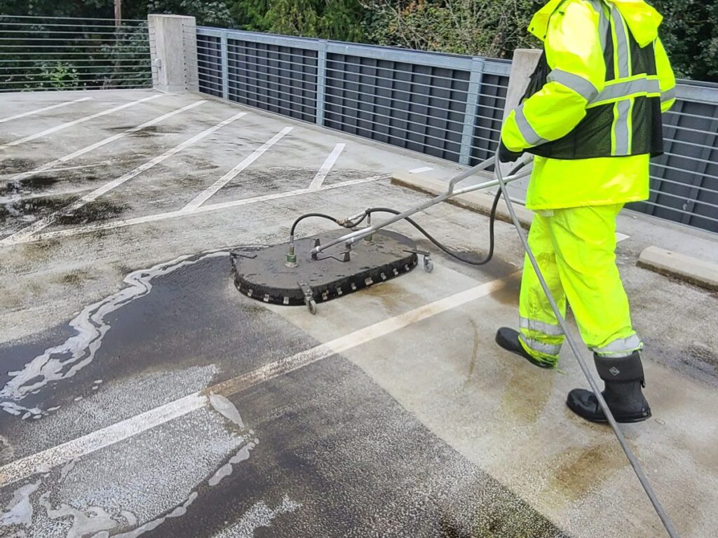 Crew pressure washing the UW Bothell parking garage deck with a surface cleaner